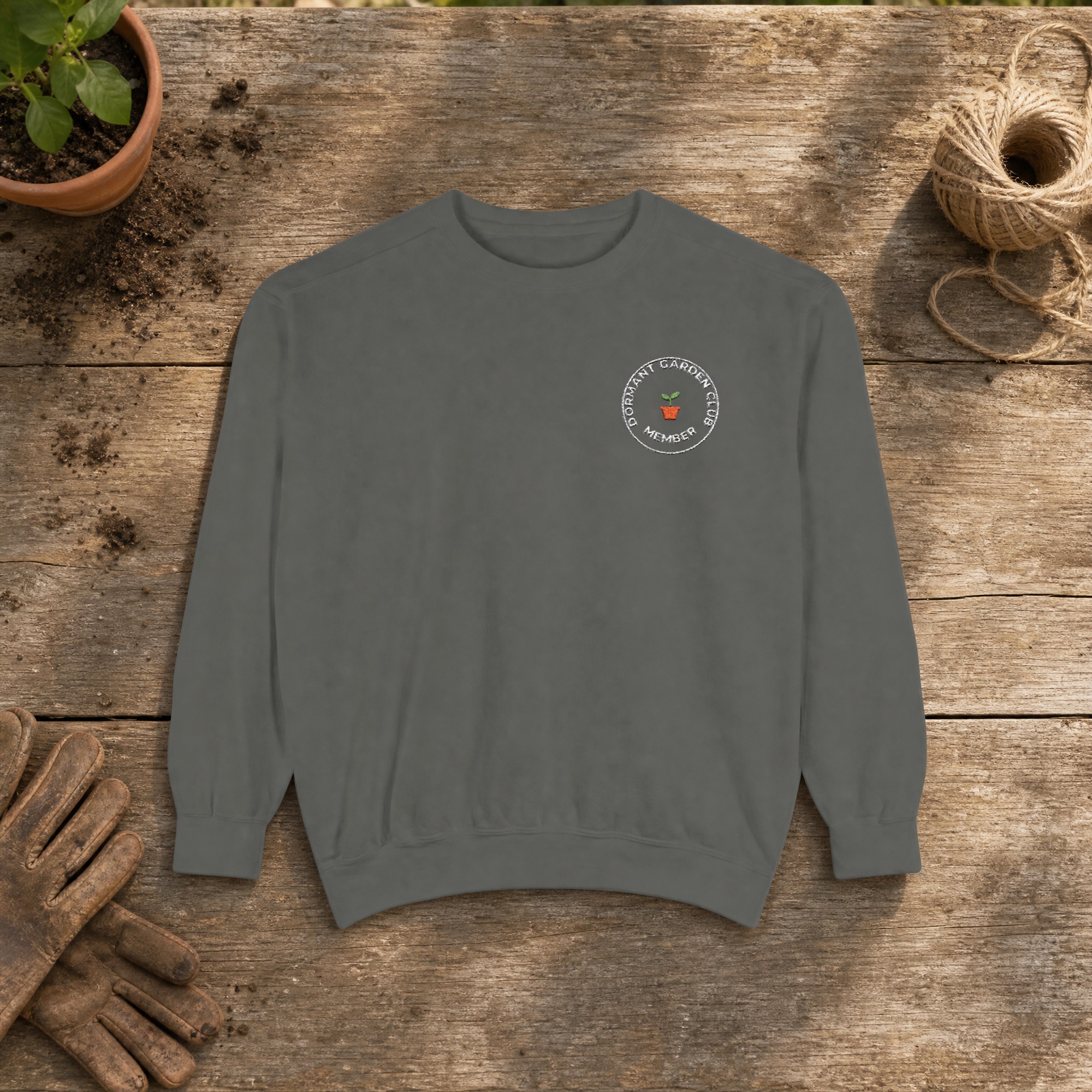 Dormant Garden Club Member Embroidered Sweatshirt in Pepper, an embroidered crewneck sweatshirt on a potting bench