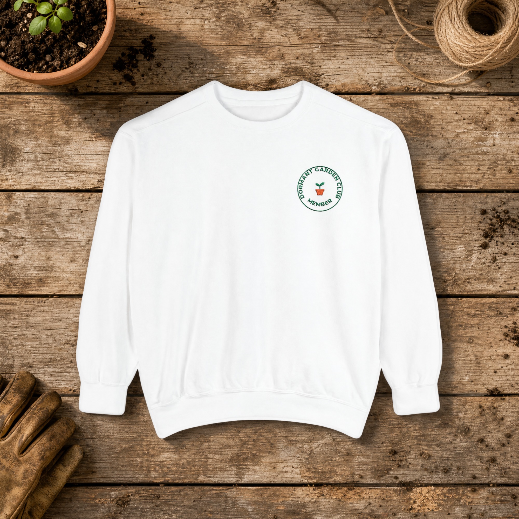 Dormant Garden Club Member Embroidered Sweatshirt in White, an embroidered crewneck sweatshirt on a potting bench
