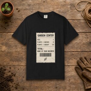 Garden Center Receipt gardening t-shirt in Black, laid flat on a potting bench with gardening gloves and a trowel