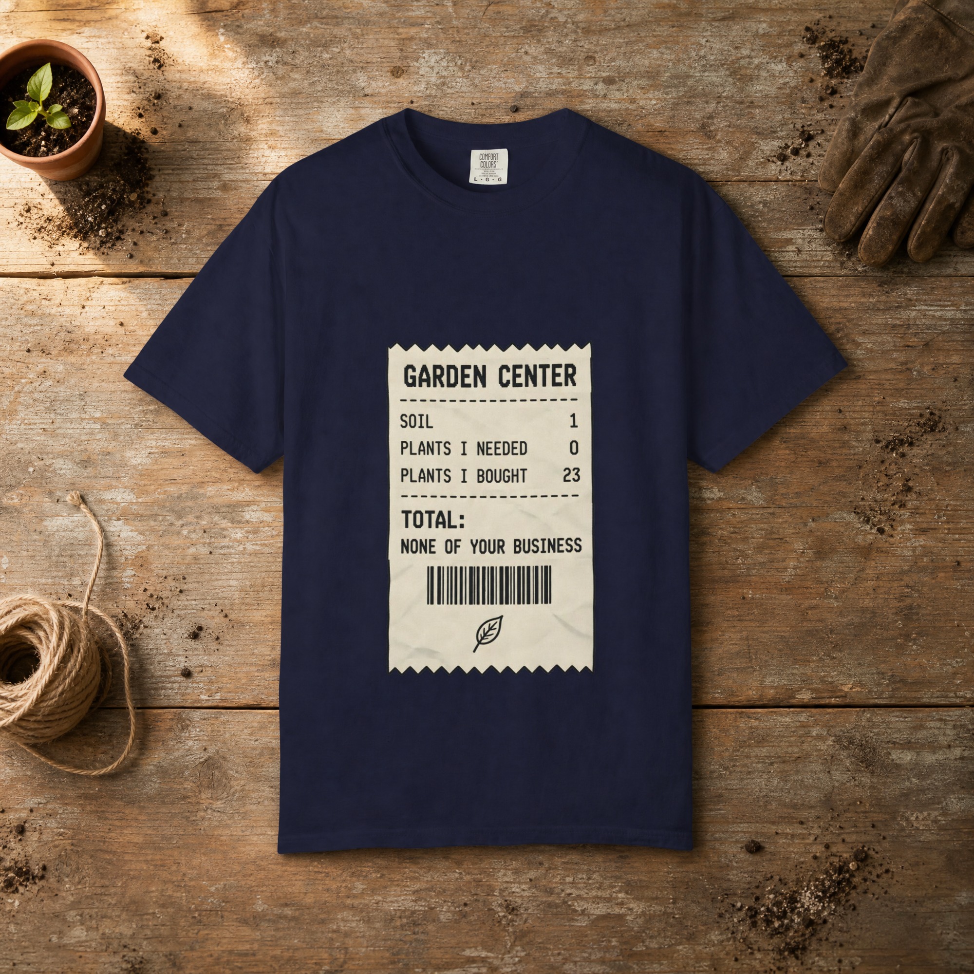 Garden Center Receipt gardening t-shirt in True Navy, laid flat on a potting bench with gardening gloves and a trowel