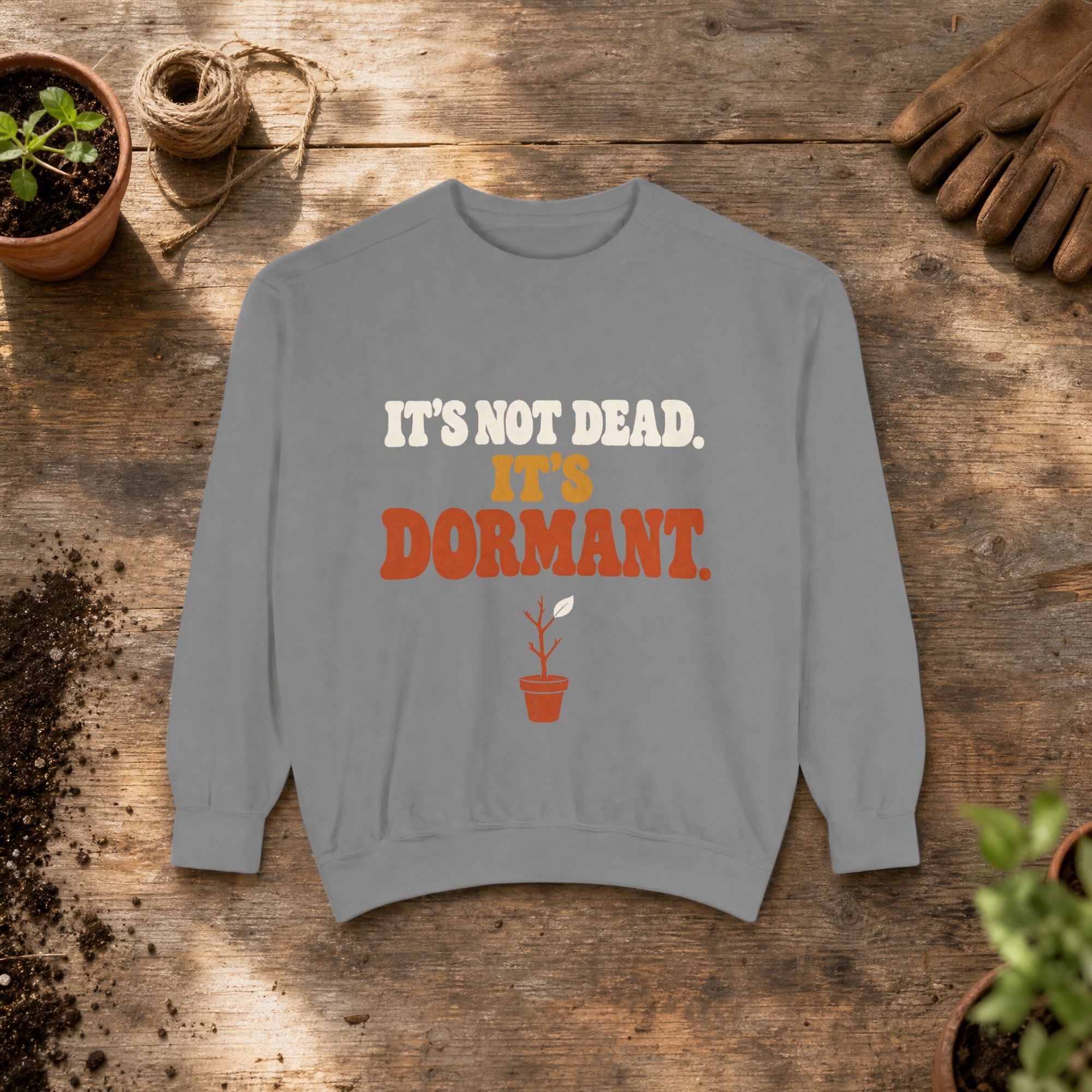 It's Not Dead. It's Dormant. Sweatshirt in Grey, a crewneck sweatshirt on a potting bench