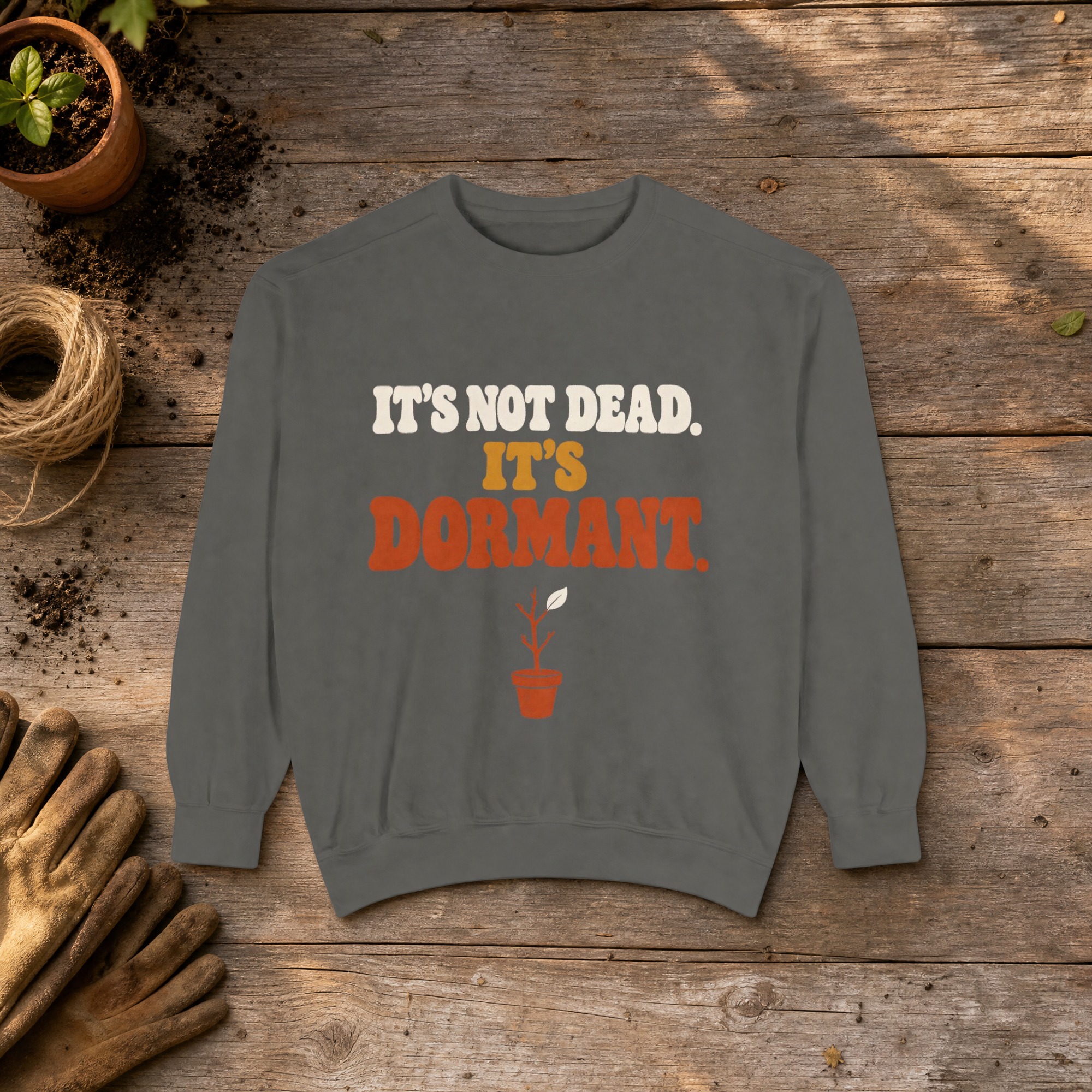 It's Not Dead. It's Dormant. Sweatshirt in Pepper, a crewneck sweatshirt on a potting bench