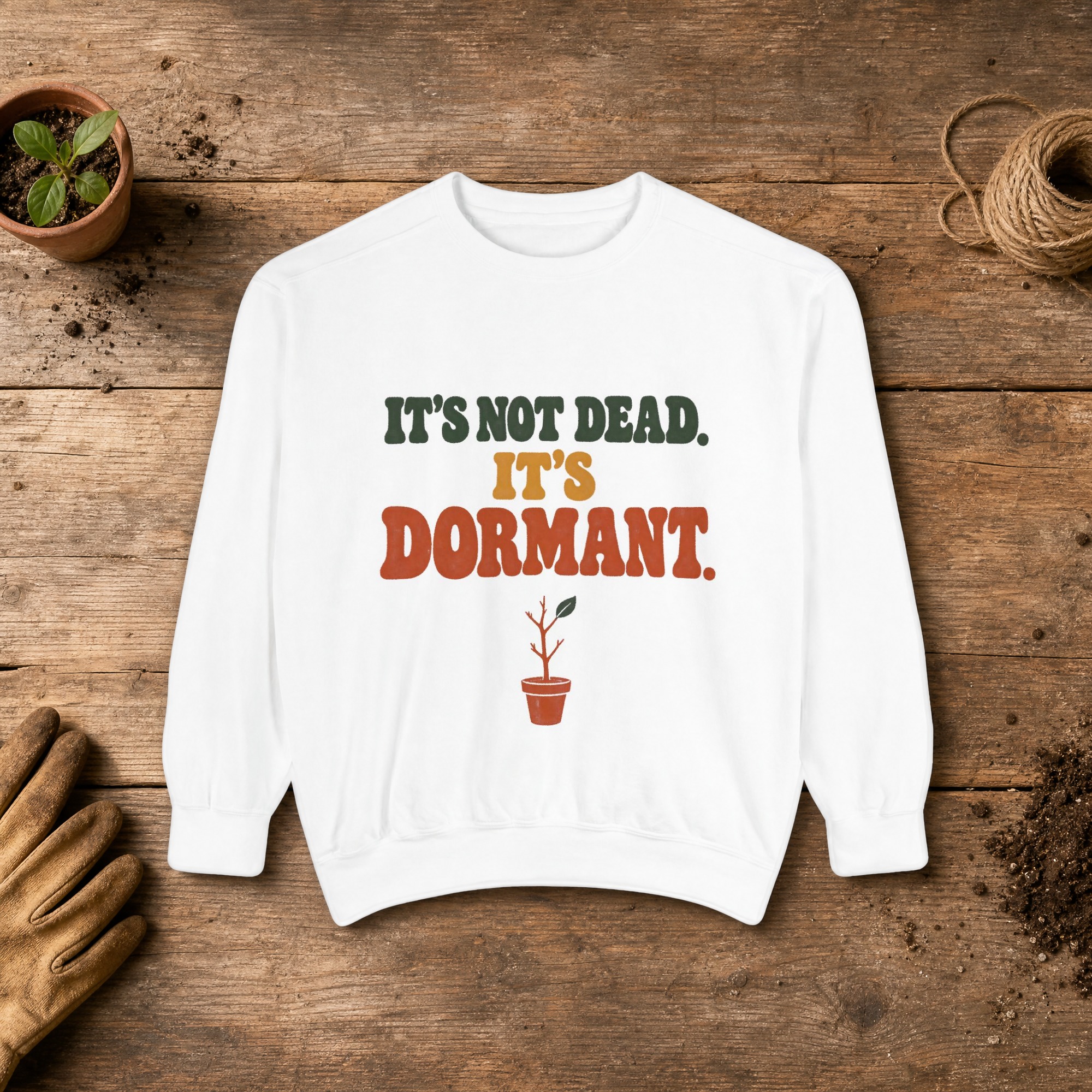 It's Not Dead. It's Dormant. Sweatshirt in White, a crewneck sweatshirt on a potting bench