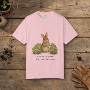 Only Here for the Lettuce gardening t-shirt in Blossom, laid flat on a potting bench with gardening gloves and a trowel
