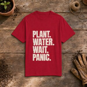 Plant. Water. Wait. Panic. gardening t-shirt in Red, laid flat on a potting bench with gardening gloves and a trowel